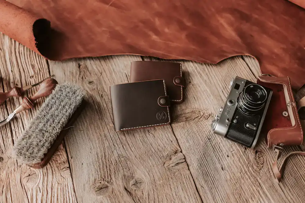 Array of finished leather wallets and belts on a wooden workbench