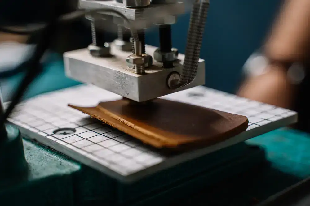 Close up of raw leather hides and solid brass hardware on a cutting mat