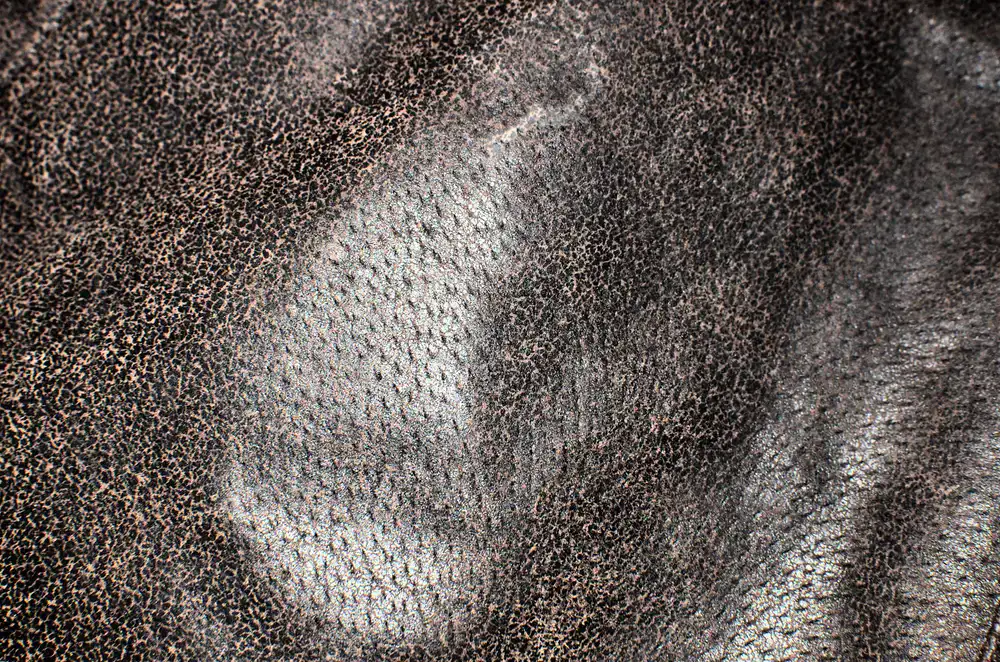 Close up of a thick leather hide being cut with a traditional blade