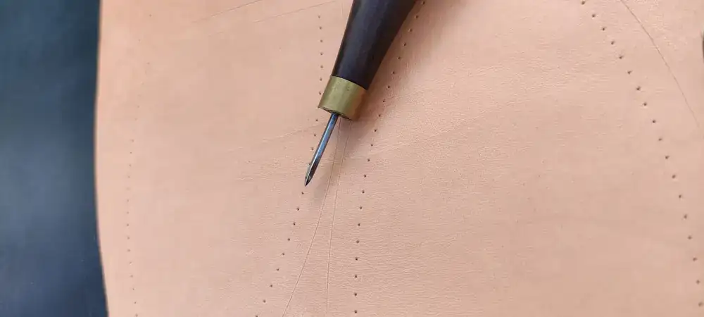 Waxed thread being pulled through thick leather with an awl
