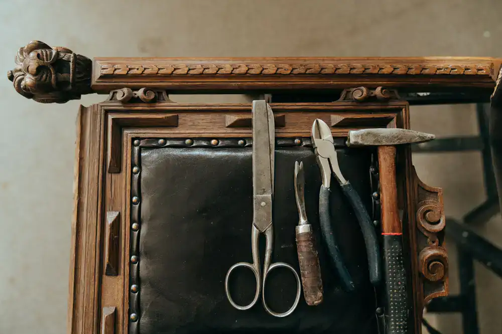 Overhead view of leatherworking tools on a scarred wooden bench