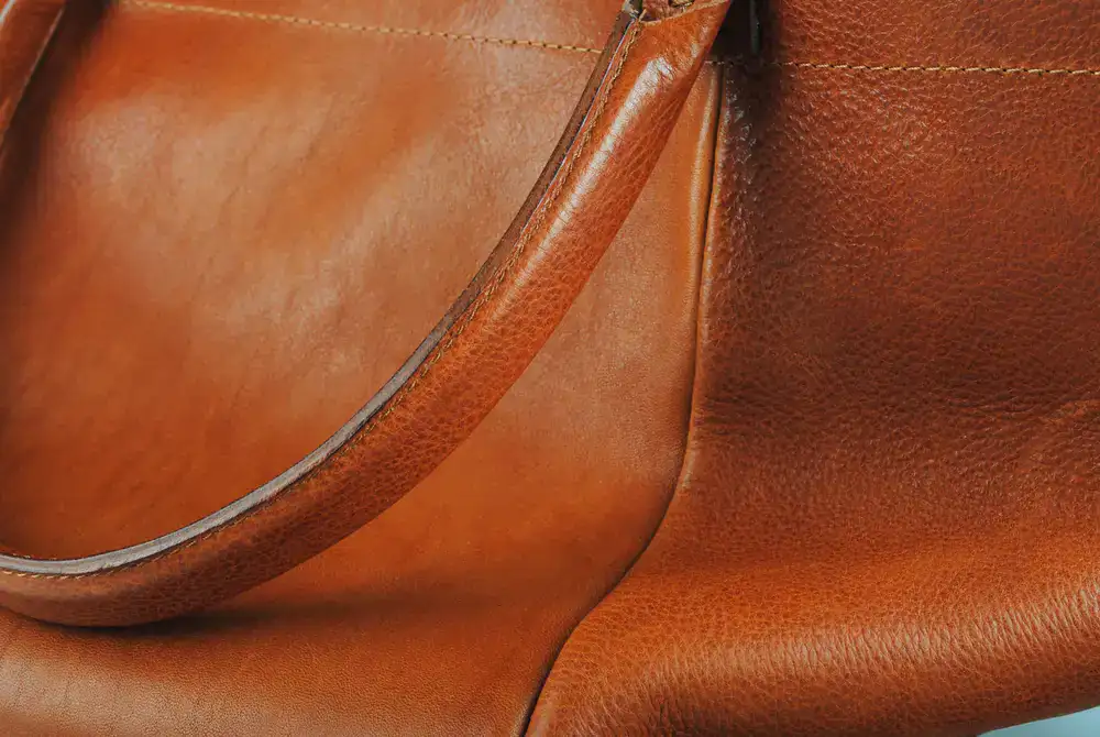 Artisan hands carefully restitching a vintage leather satchel